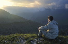 Mand mediterer tidlig morgen på bjerg.