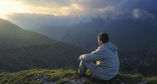 Mand mediterer tidligt på en bjergtop.